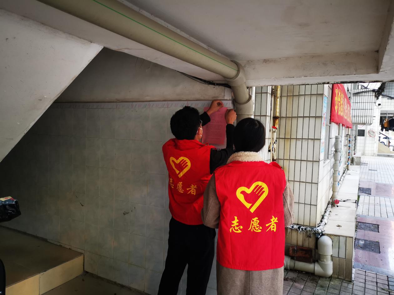 党员志愿者在社区楼道处粘贴煤气使用安全宣传单（1）